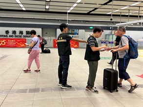 Hong Kong Customs conducted patrols during the Mainland's National Day Golden Week period at popular shopping spots in various districts and reminded traders to comply with the requirements of the Trade Descriptions Ordinance, with a view to safeguarding the rights of local consumers and visitors. Photo shows Customs Officers distributing pamphlets to visitors at the Heung Yuen Wai Control Point.